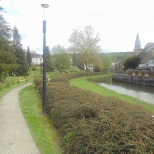 Houffalize Minigolf.  L'église, l'Ourthe, haie entre Ourthe et chemin. Le minigolf est à gauche.